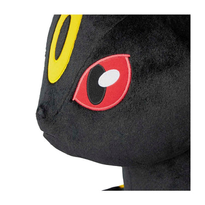 Close-up of a black plush toy with red and yellow eyes on a white background