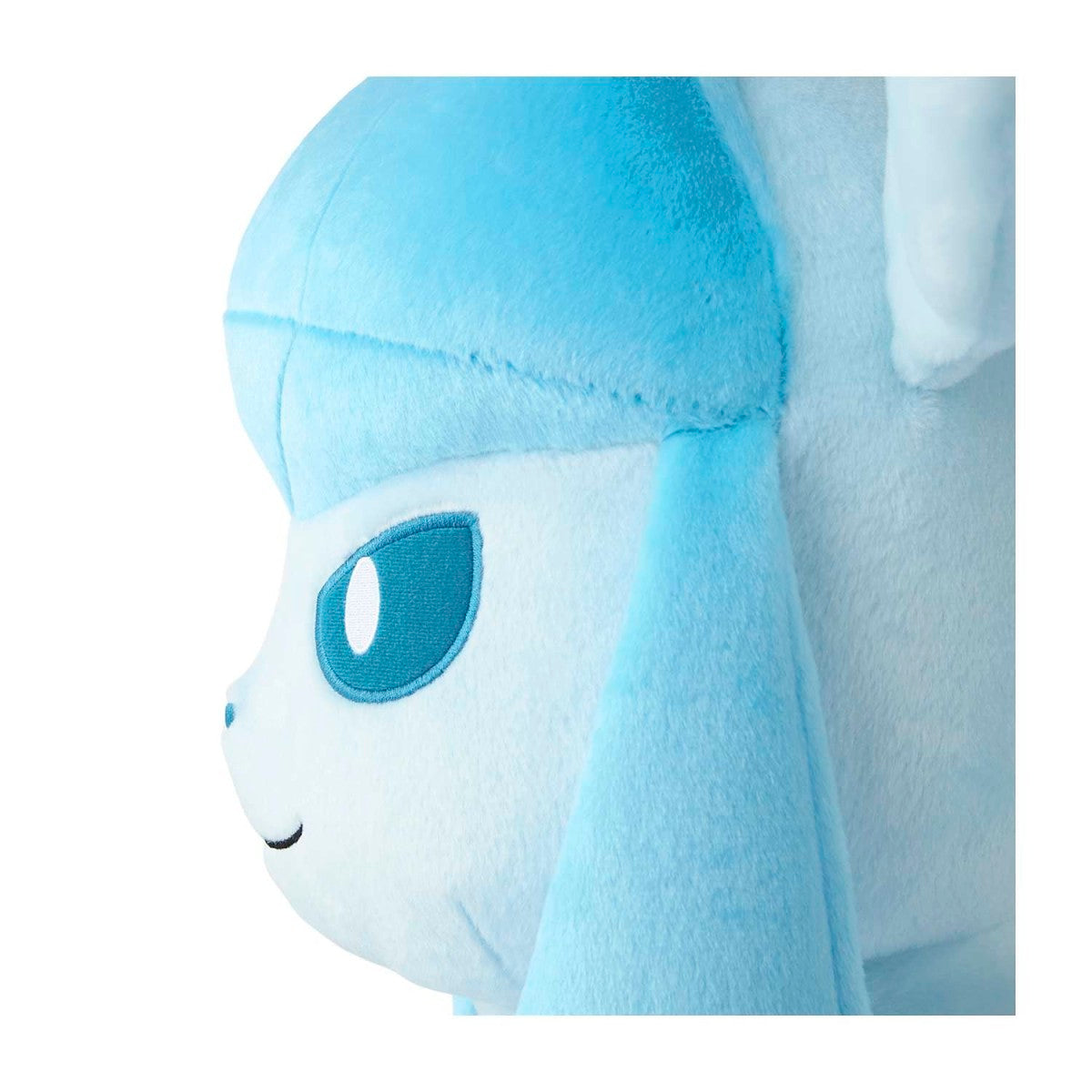 Close-up side view of a plush toy with a light blue and white color scheme, featuring a large blue eye and soft plush texture on a white background.