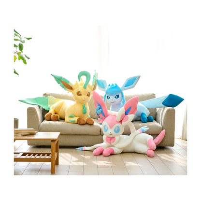 Three large plush toy Pokémon (Eevee, Gliscor, and Mew) arranged on and around a beige sofa in a bright, modern living room.