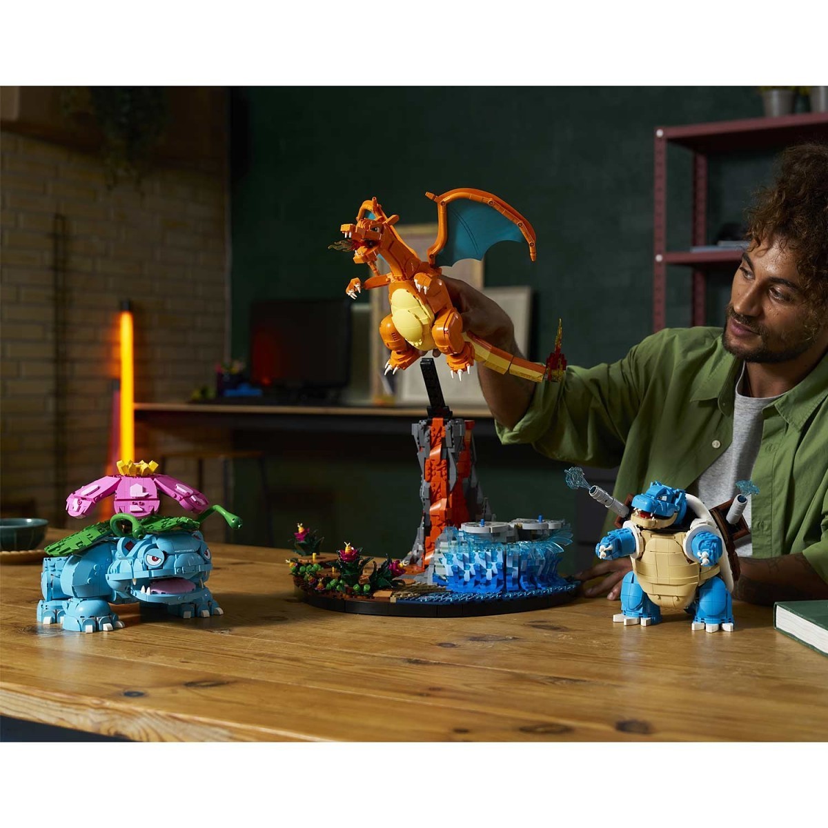 Man holding a Charizard toy with other Pokémon models on a table.